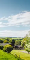 Green hills, trees and the clubhouse at Thurston Manor