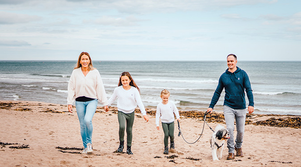 Family walking their dog on the beach at Pease Bay