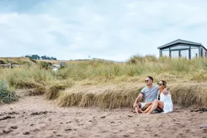 Couple sitting on the beach at Pease Bay